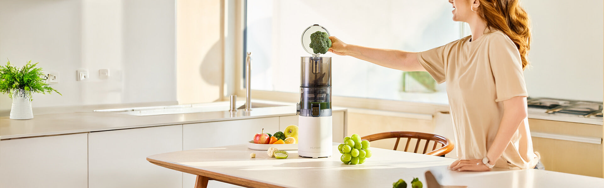 Hurom E30-ST: Eine Frau presst in der Küche frischen und gesunden Saft aus Brokkoli und Obst.