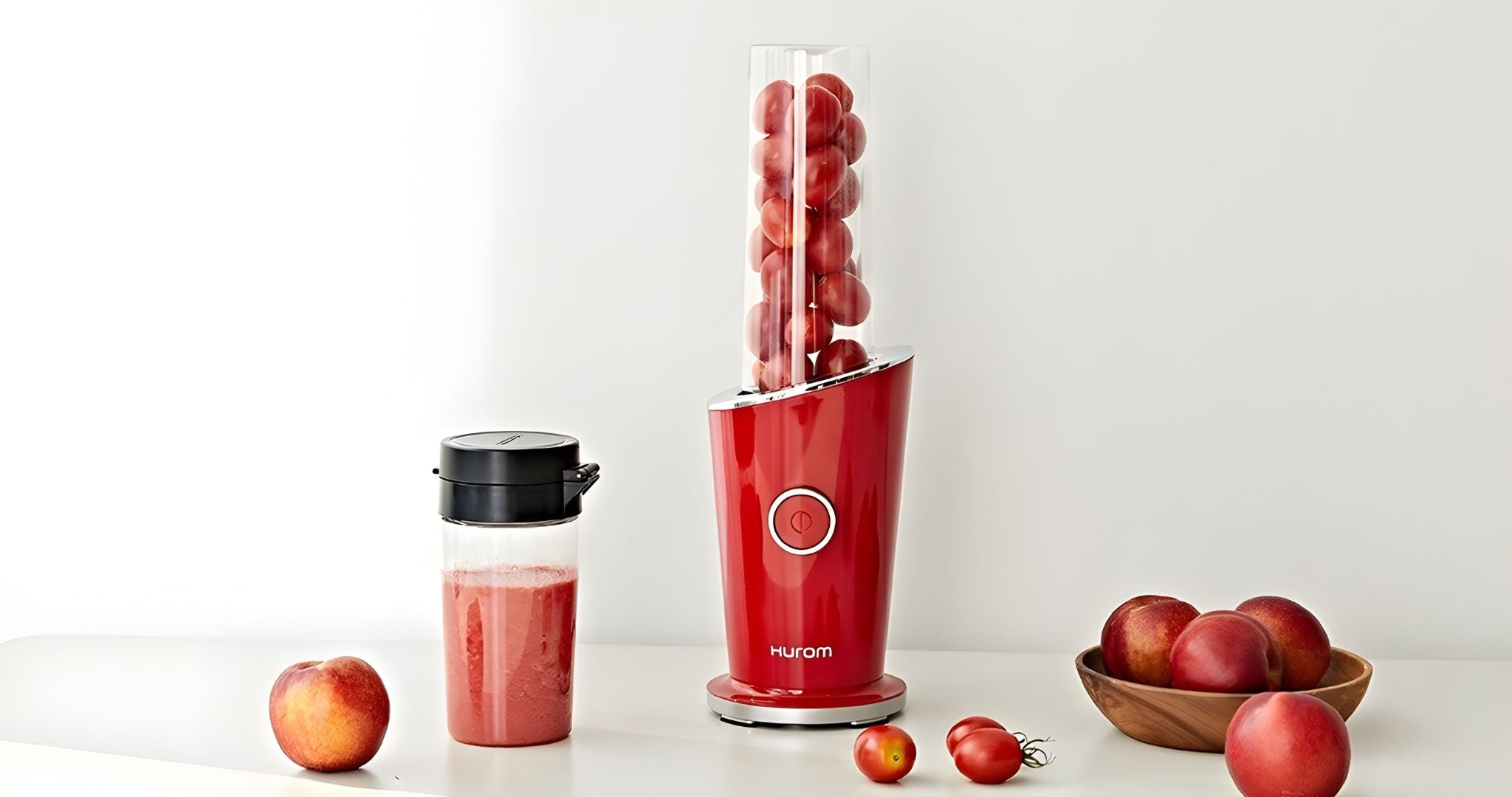 Hurom Mini Mixer mit befülltem Behälter mit Tomaten auf Küchenanrichte
