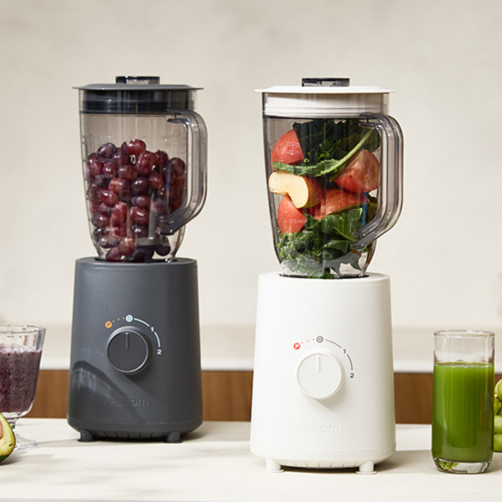 Hurom Standmixer in Milestone Gray befüllt mit Weintrauben und in Mushromm, befüllt mit Obst und Gemüse auf Küchenanrichte