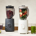 Hurom Standmixer in Milestone Gray befüllt mit Weintrauben und in Mushromm, befüllt mit Obst und Gemüse auf Küchenanrichte
