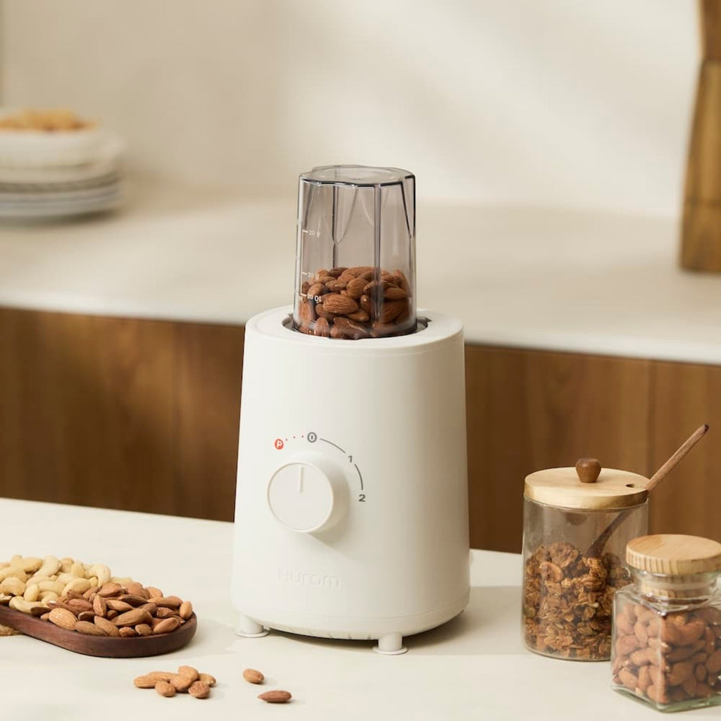 Hurom Standmixer mit Mahlaufsatz, befüllt mit Mandeln auf Küchenanrichte