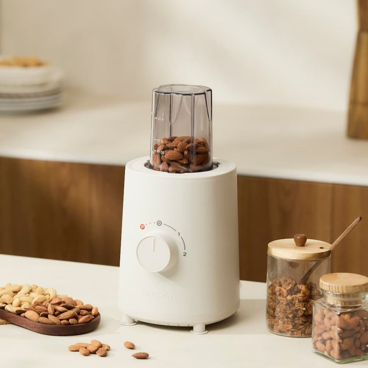 Hurom Standmixer mit Mahlaufsatz, befüllt mit Mandeln auf Küchenanrichte